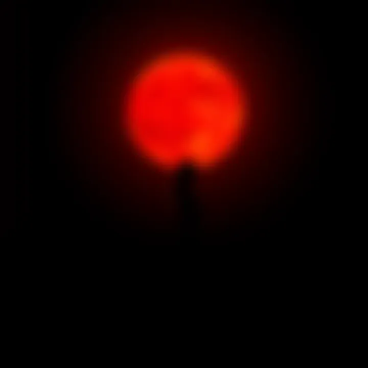 Silhouette of a woman standing under a Blood Moon, symbolizing the connection between femininity and lunar cycles